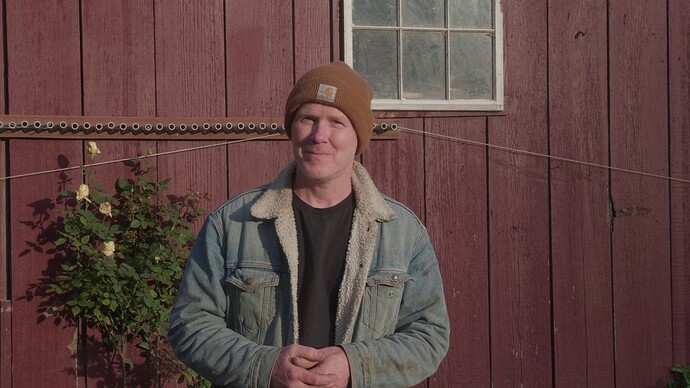 Daniel stands facing the camera in front of our barn to share his welcome message.